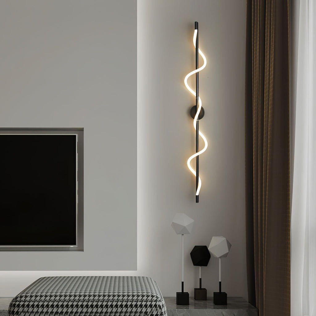 A tall black Clérachic wall light with a glowing spiral band hangs by a wall-mounted screen above a houndstooth throw.