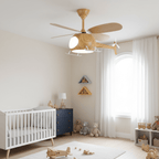 Helicopter ceiling fan from Clérachic in a pale nursery, with a white cot, a navy chest of drawers and toy planes on the rug.