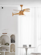 In a bright white room with sheer curtains, an arched shelf unit and a round table, a wood-grain Clérachic helicopter ceiling fan hangs overhead.