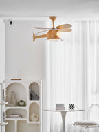 Helicopter-shaped ceiling fan from Clérachic seen from a distance in a white room, with an arched shelf unit and a white table beneath.