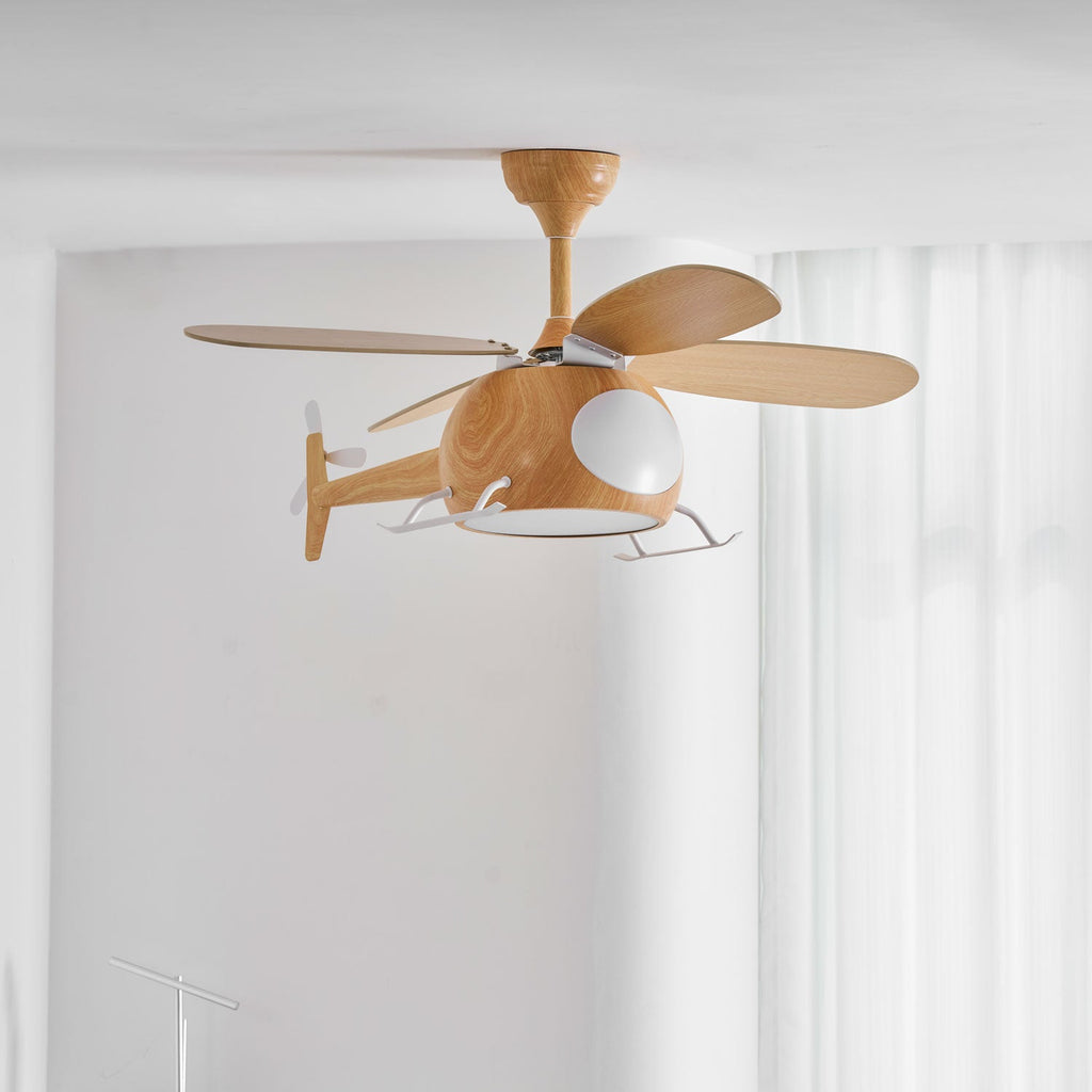 Against a white wall, this Clérachic helicopter fan shows its four wood-grain blades and white skids in front of sheer curtains.