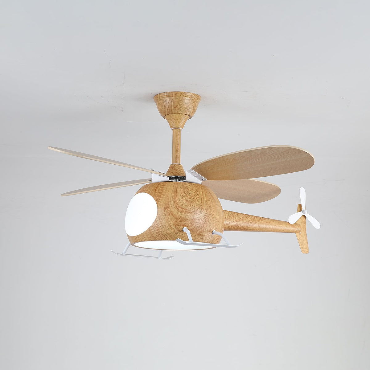 Helicopter ceiling fan from Clérachic with its light on, showing the cut-out window of the cabin, the tail rotor and four wood-grain blades.