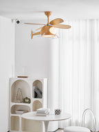 Helicopter ceiling fan from Clérachic hung in a white room with sheer curtains, an arched shelf unit and a round table with books.