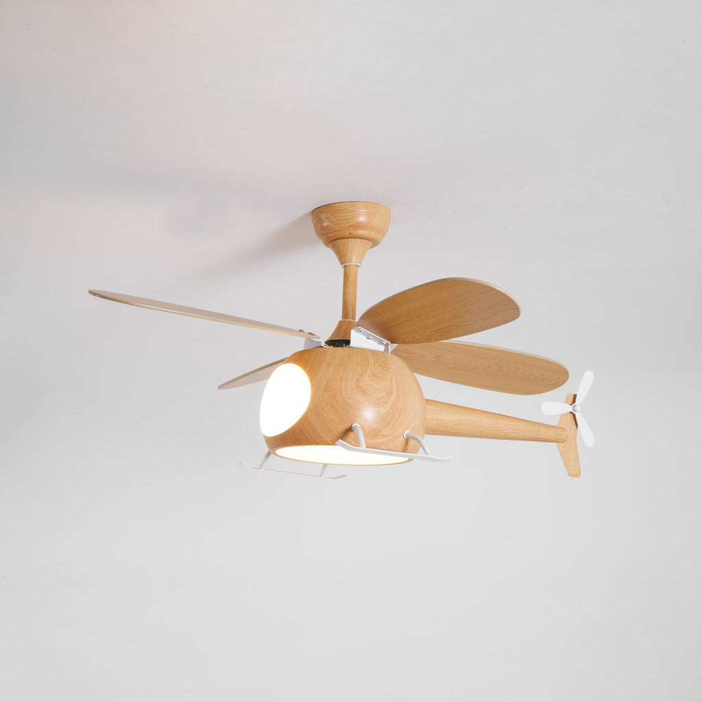 Seen from slightly below, a wood-grain Clérachic helicopter fan with its warm cabin light on against a pale grey ceiling.