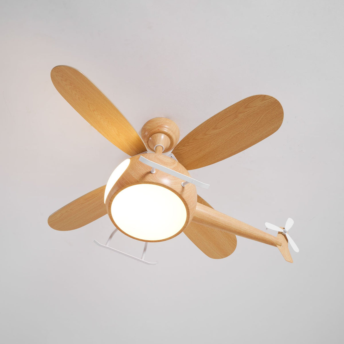 View from below of the helicopter ceiling fan from Clérachic with its round light glowing warm and its blades spread out.