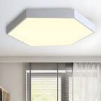 Silver-toned Clérachic hexagon flush mount ceiling light casting warm light beside a curtained window.