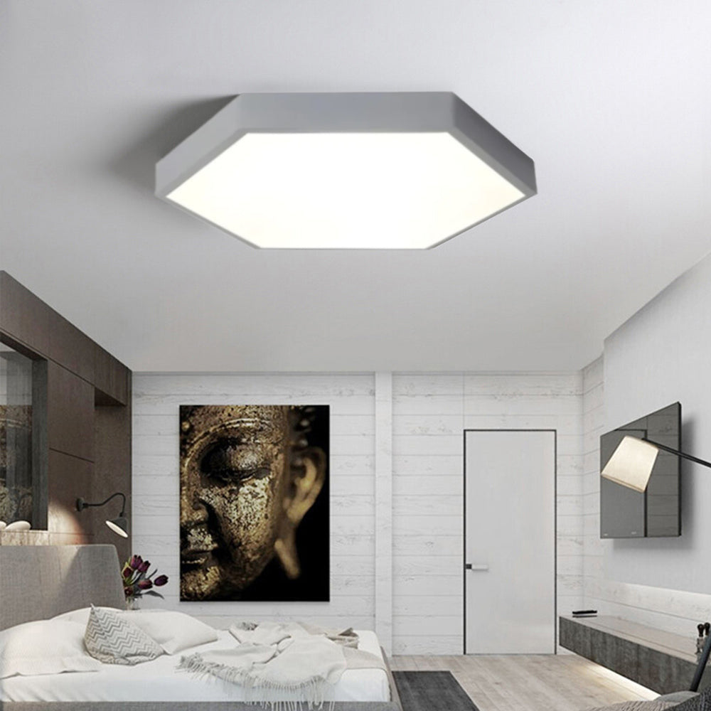 Gray Clérachic hexagon ceiling light centered over a bedroom styled with framed wall art and a reading sconce.