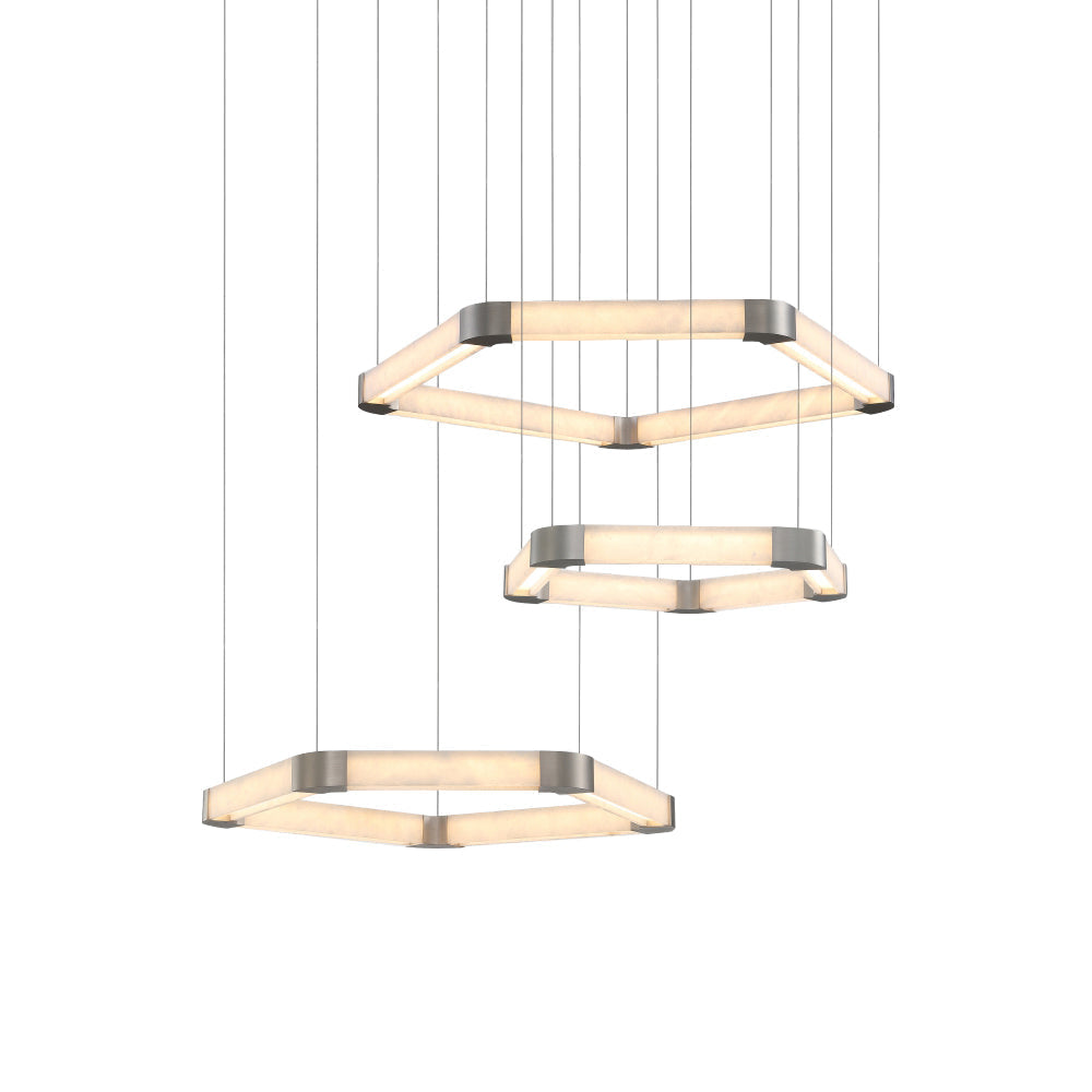 All three sizes of the Clérachic Hexagonal Alabaster Chandelier hung at staggered heights and lit against a plain backdrop.