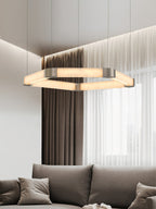 The Clérachic Hexagonal Alabaster Chandelier hung above a grey sofa, warm stone light against sheer curtains and a city view.
