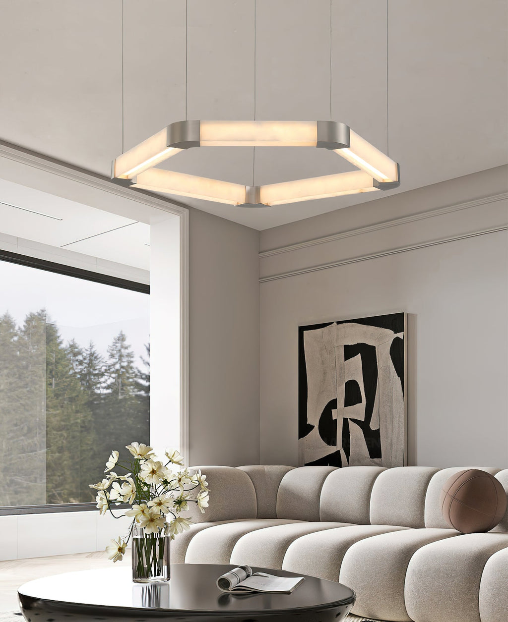Wide view of a Clérachic Hexagonal Alabaster Chandelier lighting a living room, above a black coffee table and pale sofa.