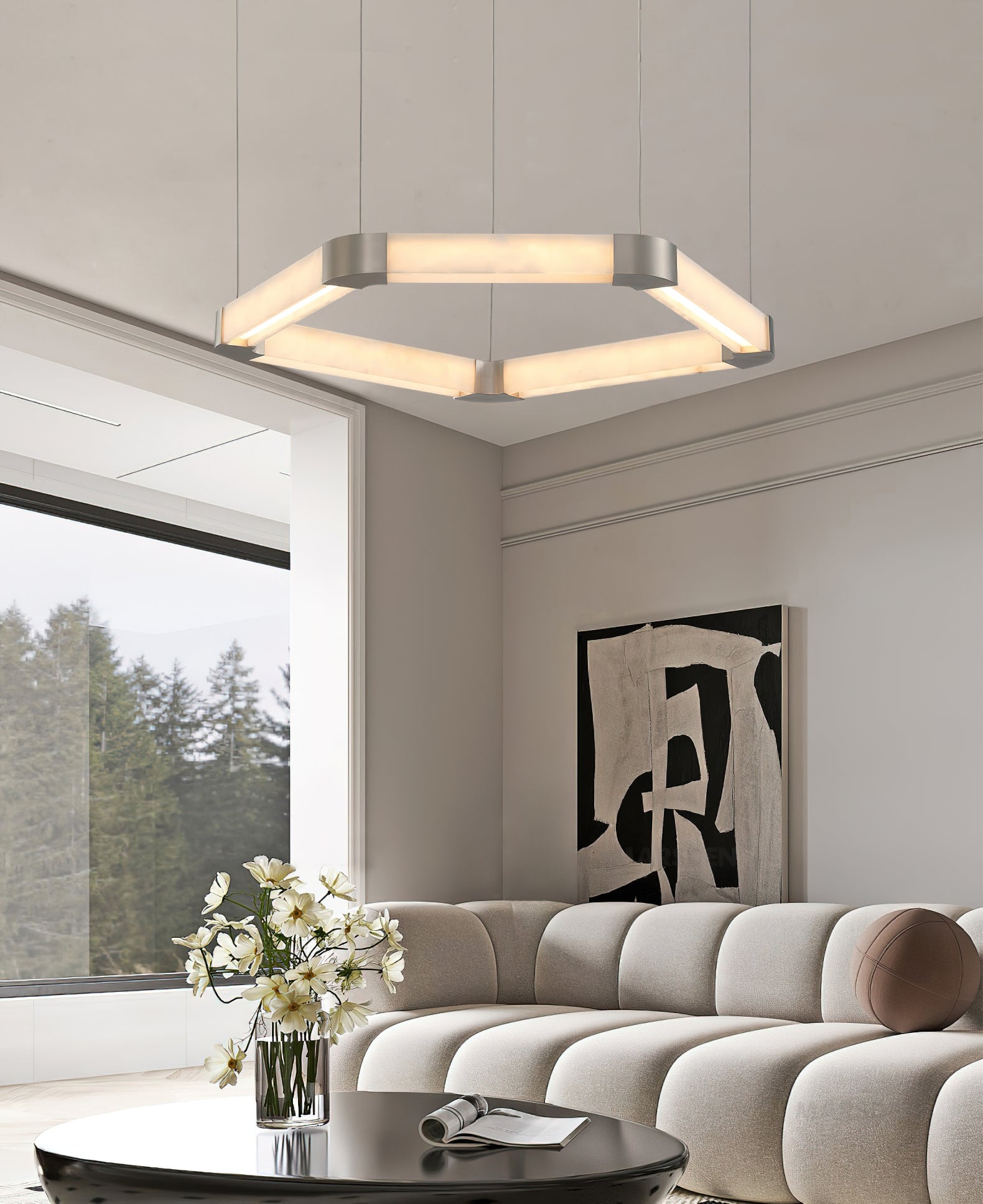 Wide view of a Clérachic Hexagonal Alabaster Chandelier lighting a living room, above a black coffee table and pale sofa.