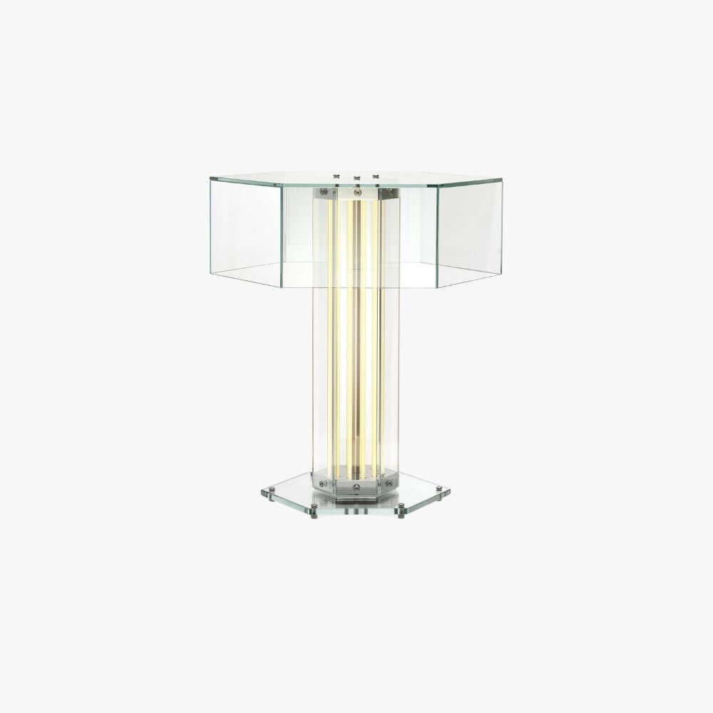 Hexagonal clear-glass table lamp with a lit column of light tubes and a flat glass base, from Clérachic, on a plain white backdrop.