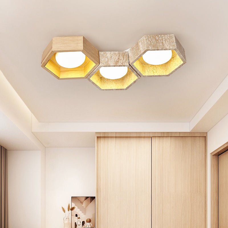 Three-cell version of this Clérachic travertine ceiling light over a wardrobe wall in pale wood, glowing warm gold.