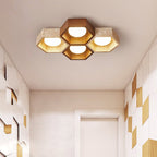 Four-cell Clérachic ceiling light with a dark walnut centre hexagon, above a hallway with geometric wood and white wall panels.