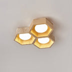 Three lit hexagons, one in light wood and two in travertine, of this Clérachic ceiling light against a soft grey backdrop.