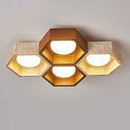 Close view of a four-cell Clérachic ceiling light with a dark walnut centre hexagon and travertine sides, all lit, on grey.