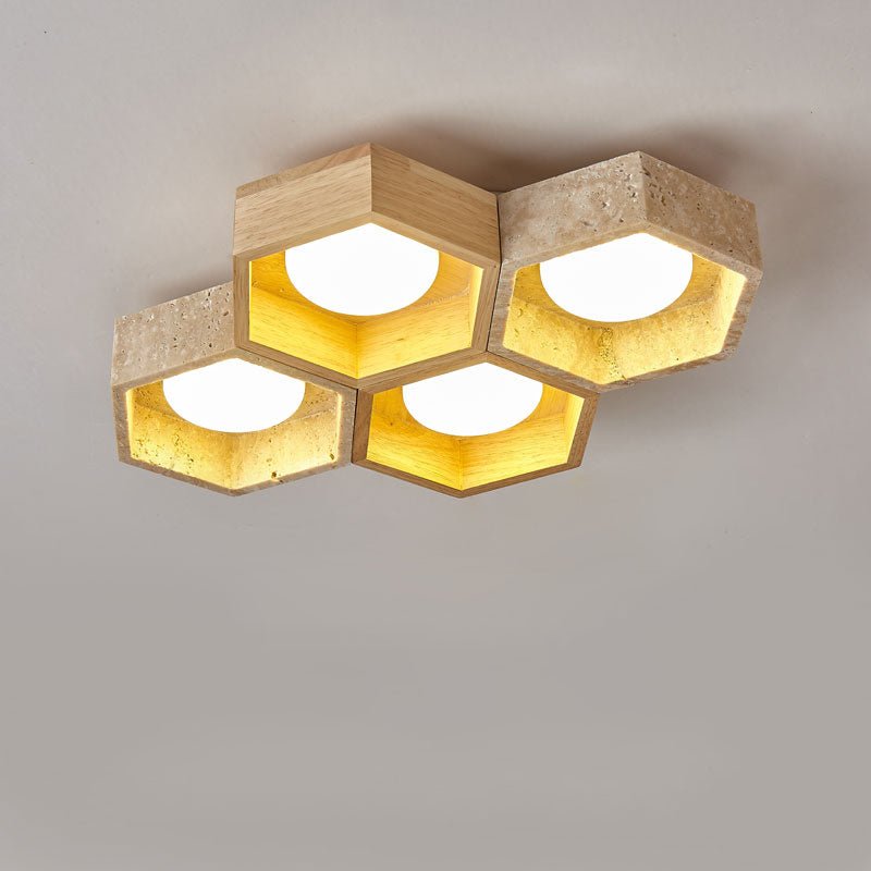 Five hexagonal cells of this Clérachic ceiling light in a tight cluster, travertine and light wood, lit warm gold on grey.
