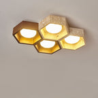 Four lit hexagons of this Clérachic ceiling light, one dark walnut cell beside pale travertine ones, against a grey backdrop.