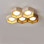 Five-cell Clérachic ceiling light with travertine hexagons on top and two walnut-toned cells at the lower right, all lit.