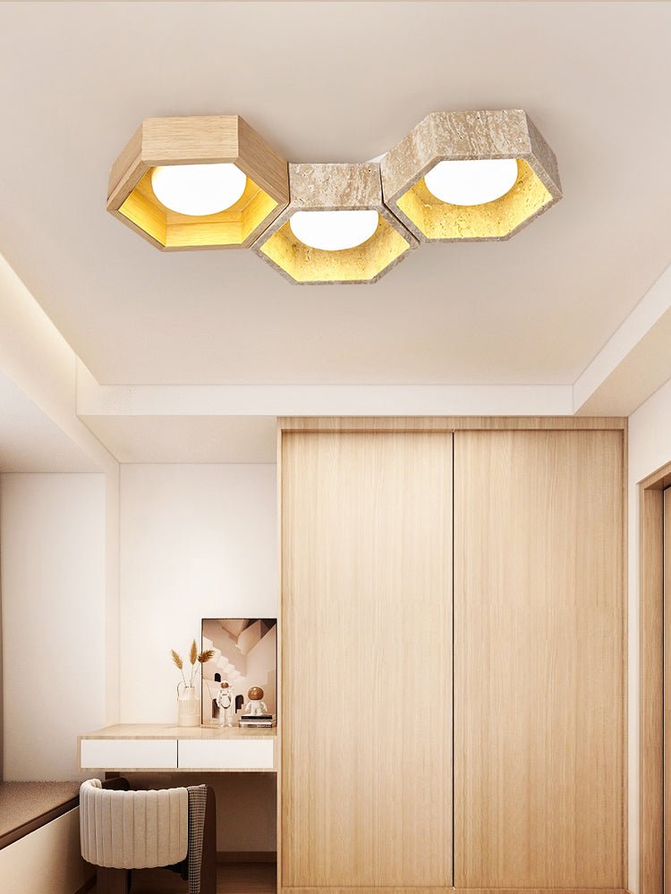 Three-cell Clérachic ceiling light over a wardrobe and dressing table, the hexagons lit warm gold in a pale bedroom.