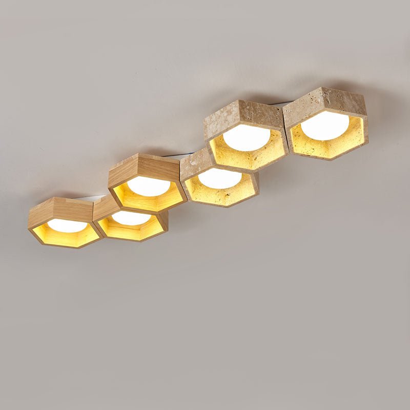 Seven hexagons stepping diagonally across the frame, a long Clérachic ceiling light in travertine and wood, lit on grey.