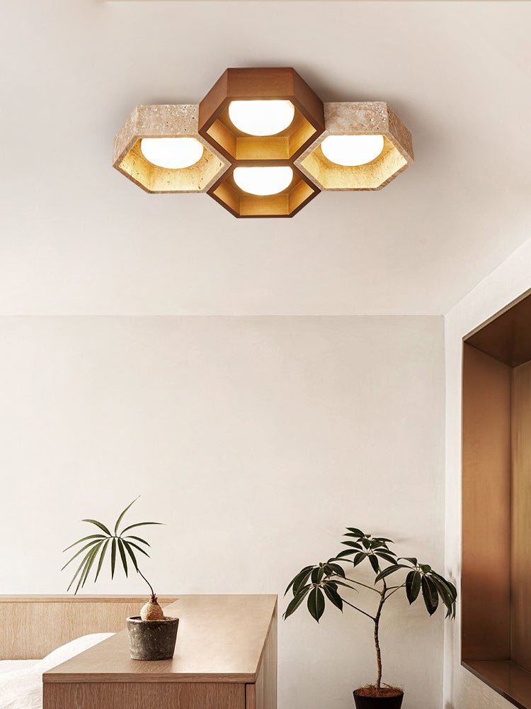 Four-cell Clérachic ceiling light with a walnut centre, hung over a pale wall beside a wooden console and potted plants.