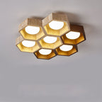 Seven-cell Clérachic honeycomb ceiling light, mostly travertine with one dark walnut cell, lit warm against a grey ceiling.