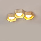 Three-cell Clérachic ceiling light in a stepped line, travertine and light wood hexagons with a gold glow, on grey.