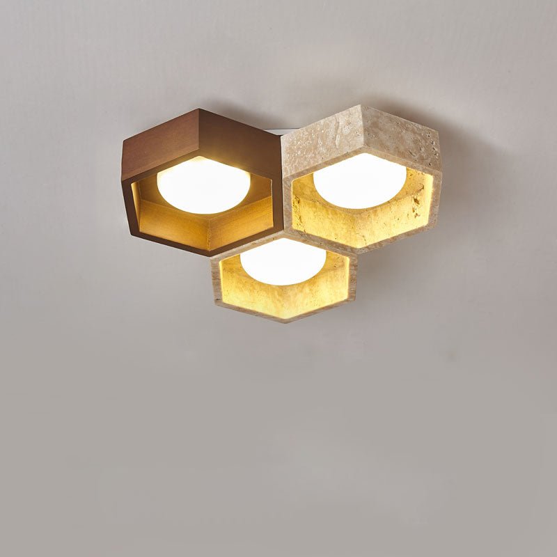 Three lit hexagons, one walnut-toned and two travertine, grouped on this Clérachic ceiling light against a grey ground.