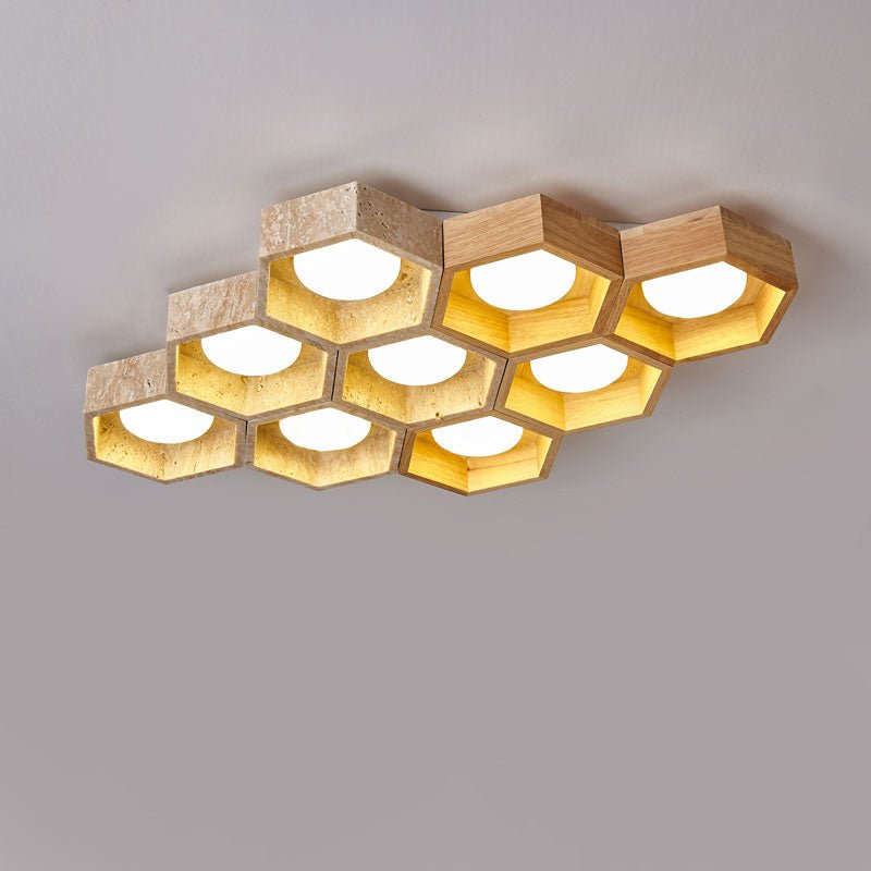 Ten travertine hexagons of this Clérachic ceiling light packed into a wide honeycomb, glowing gold on a grey backdrop.