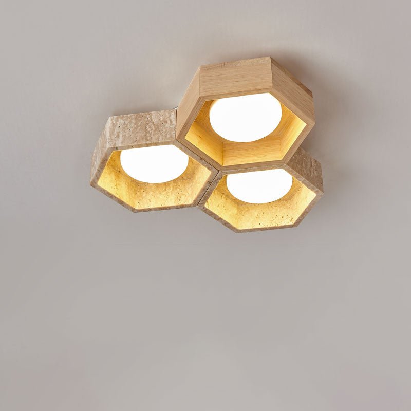 Close view of three hexagons of this Clérachic ceiling light, travertine and light wood, each with a bright diffuser.