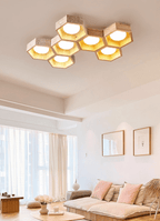 Seven-cell Clérachic ceiling light in a living room with a pink sofa, sheer curtains and two framed prints on the wall.