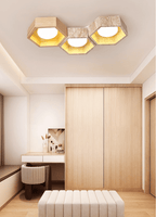 Three-cell Clérachic ceiling light above a dressing table and a cream upholstered stool, with a wood wardrobe behind.