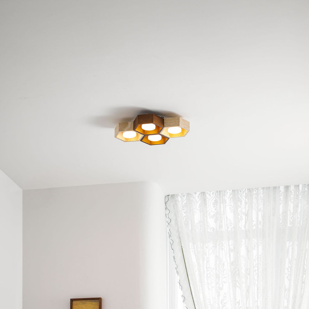 Distant view of a four-cell Clérachic ceiling light, small against a white ceiling, beside a lace-curtained window.