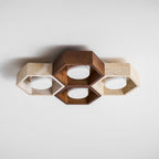 Four-cell Clérachic ceiling light with a dark walnut centre and travertine sides, lit white discs, on a white ceiling.