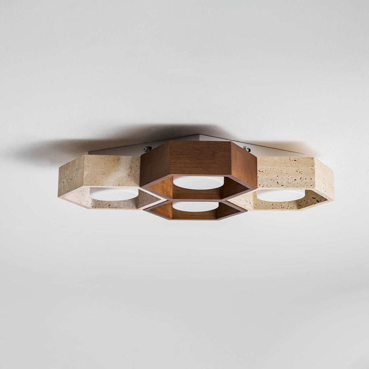 Side-on view of this Clérachic ceiling light showing how shallow the walnut and travertine hexagons sit against the ceiling.