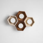 Top-down view of four hexagons, two walnut and two travertine, with round openings, on a plain white backdrop from Clérachic.