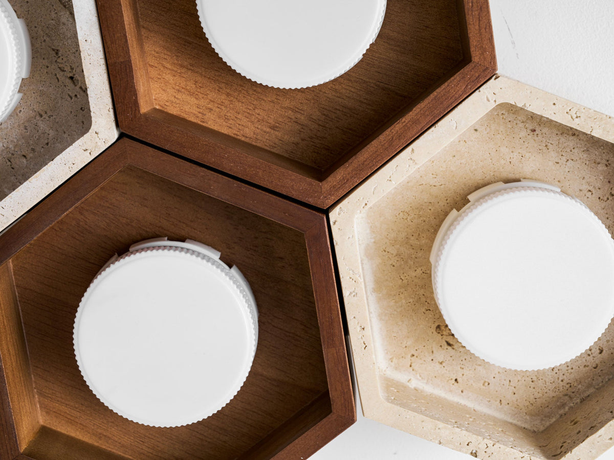 Close view of walnut and travertine hexagon cells on this Clérachic ceiling light, with the white disc lamps visible inside.