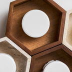 Close view of a walnut hexagon on this Clérachic ceiling light, showing the white ribbed disc lamp inside the wood frame.