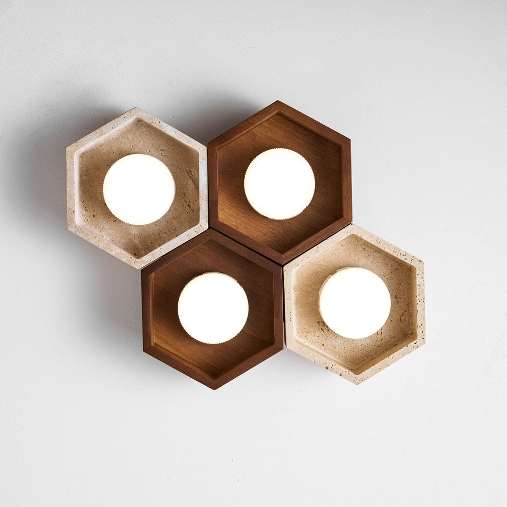 Four lit hexagons, two walnut and two travertine, of this Clérachic ceiling light shown from below on a pale backdrop.