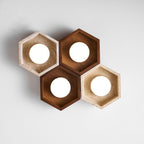Four lit hexagons, two walnut and two travertine, of this Clérachic ceiling light shown from below on a pale backdrop.