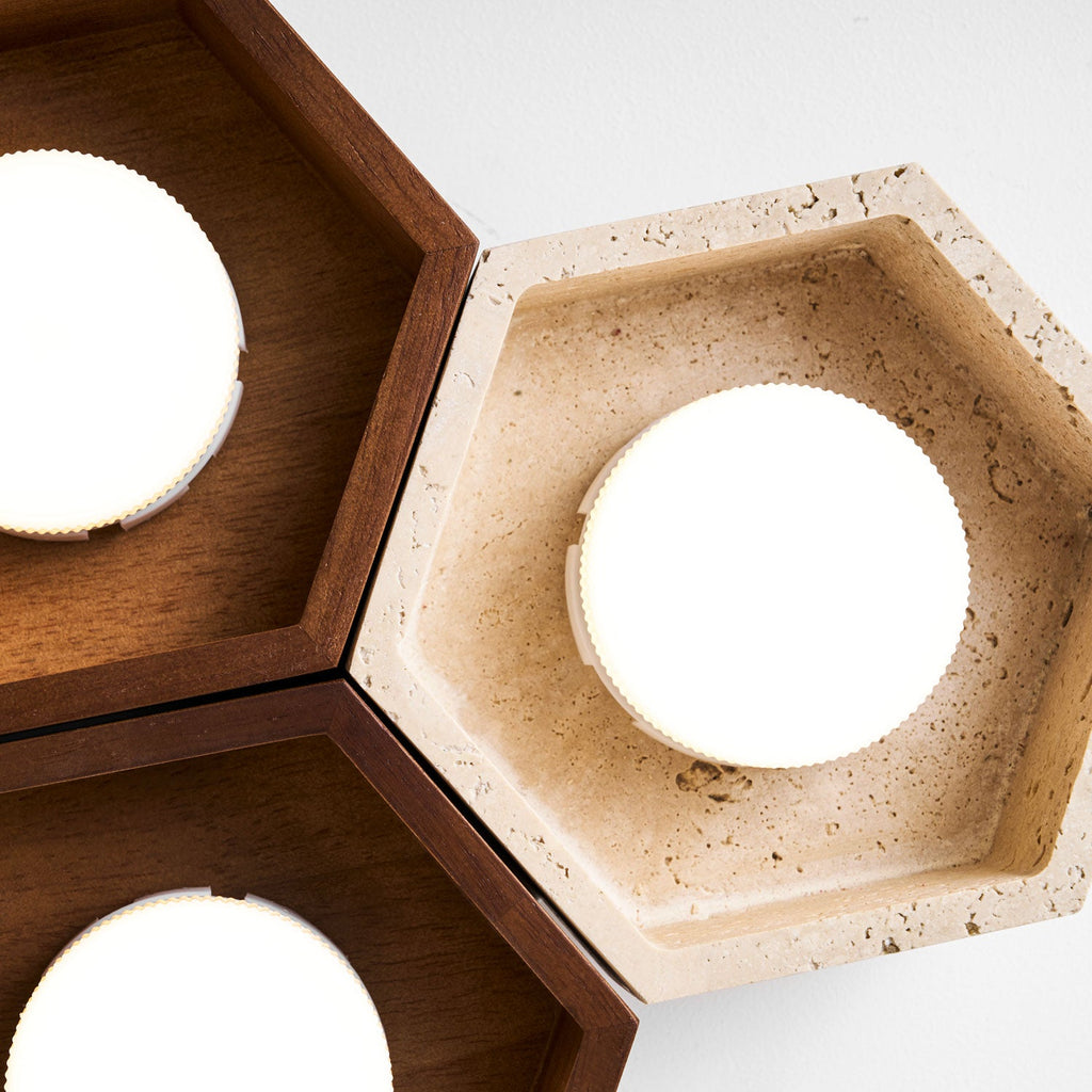 Close view of a travertine hexagon on this Clérachic ceiling light, with the stone's pitted surface and a glowing disc.