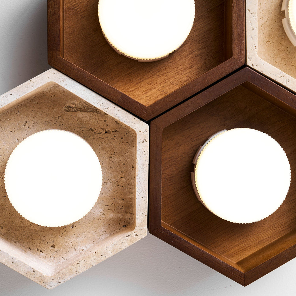 Close view of lit disc lamps in travertine and walnut hexagons on this Clérachic ceiling light, the grain clearly visible.
