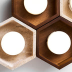 Close view of lit disc lamps in travertine and walnut hexagons on this Clérachic ceiling light, the grain clearly visible.