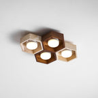 Four lit hexagons, walnut and travertine, of this Clérachic ceiling light seen at an angle against a white ceiling.
