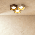 Clérachic ceiling light of three hexagonal walnut and travertine frames, each with a gold-leaf interior and a lit opal glass globe.