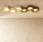 Clérachic six-head ceiling light, a long honeycomb of travertine and walnut hexagons with gold-leaf interiors and glowing globes.