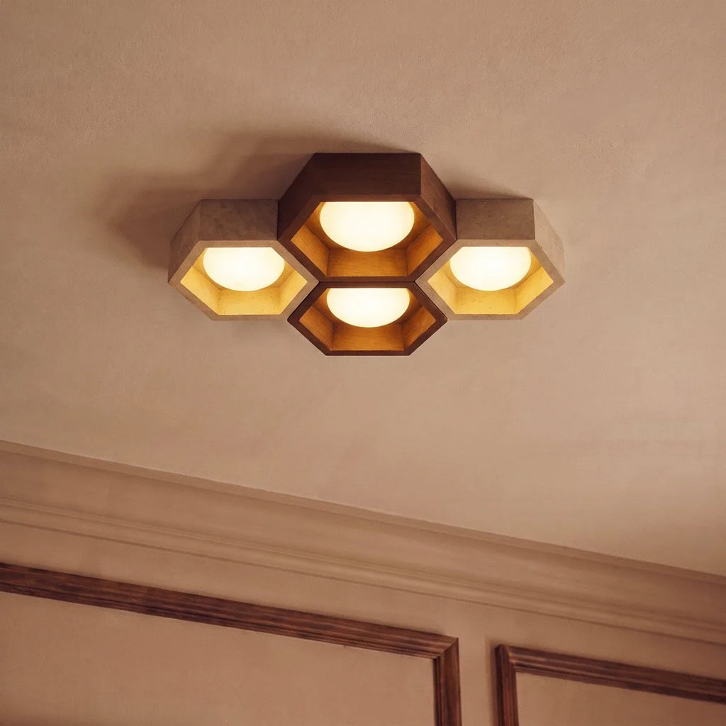 Clérachic four-head ceiling light seen from below, walnut and travertine hexagons with gold-leaf linings beside cornice mouldings.
