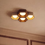Clérachic four-head ceiling light seen from below, walnut and travertine hexagons with gold-leaf linings beside cornice mouldings.