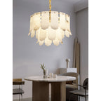 Warm light from the Clérachic Hue Alabaster Chandelier falling over a round marble dining table and its low chairs.